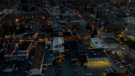 aerial hyperlapse traffic zooms through small town, transition to from dusk to night, main street lights turn on, timelapse, time lapse