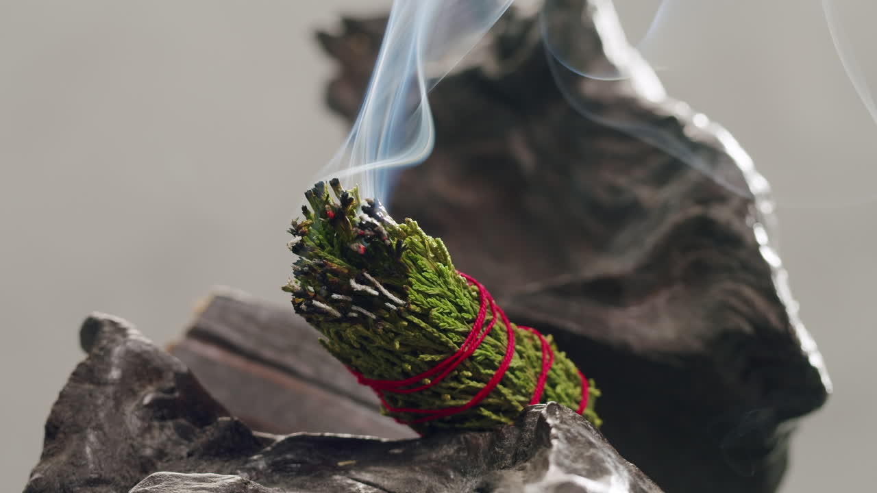 Person holding Palo Santo wood stick in hand, aromatic Palo Santo burning on black background, smoke spreading around, slow motion video clip, high quality 4k close up footage. High quality 4k footage
