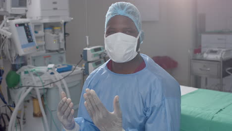 portrait of african american male surgeon wearing surgical gown in operating theatre, slow motion