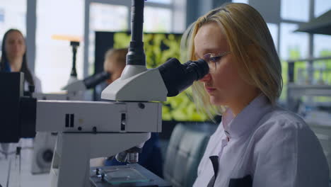 estudiantes usando microscopios en un laboratorio