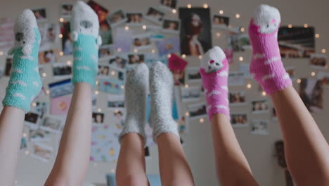 happy teen girls lying on bed at home with legs up having fun wiggling feet hanging out wearing pajamas enjoying relaxing morning on weekend