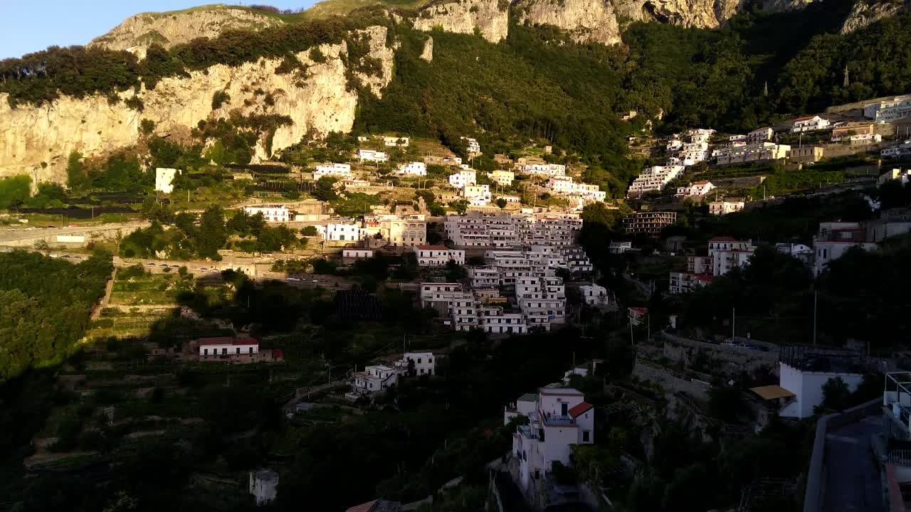 Pan to the right of the camera revealing the heights of the city of Amalfi, with beautiful houses and buildings located on the sides of a mountain