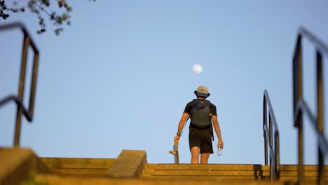 teen walking with skateboard with moon in the sky