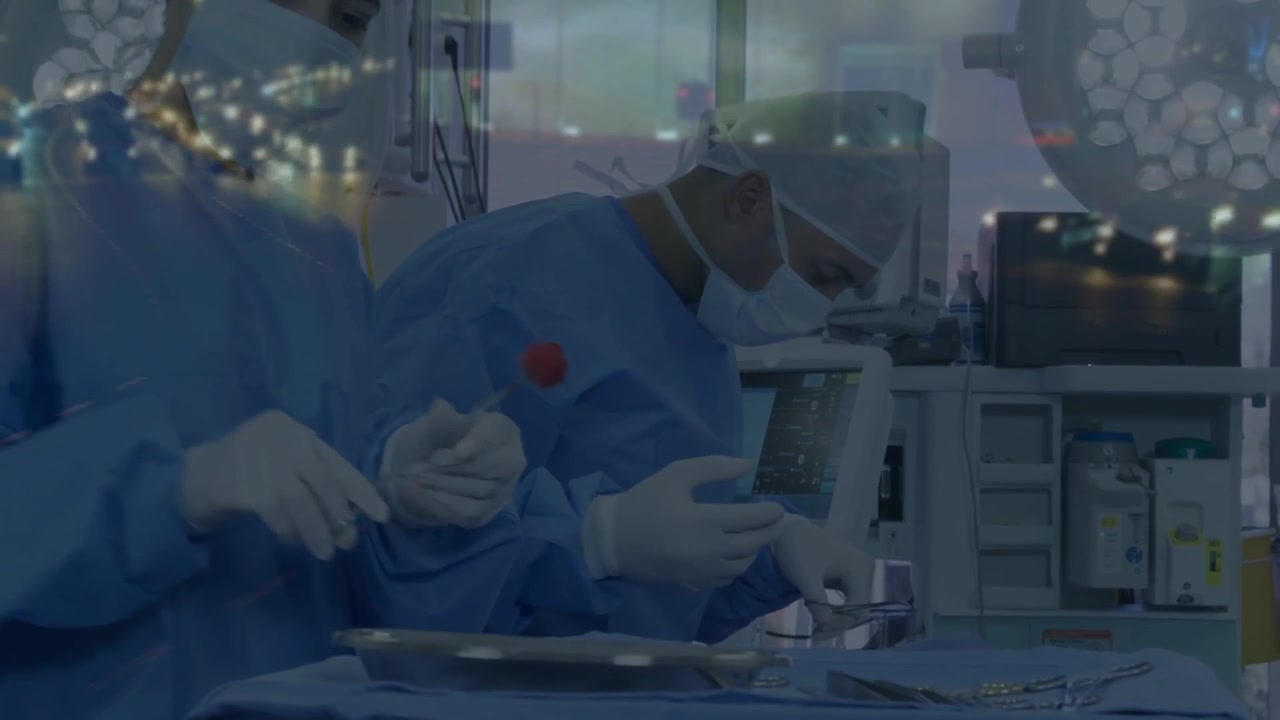 Surgeon initiating surgery by lifting red tool, assistant passing clamps, monitor displaying vitals