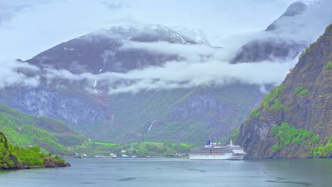 Time-lapse-of-luxury-cruise-ship-in-fjord,-mysterious-low-cloud-around-mountain