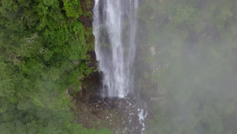 Antena-De-Arriba-Hacia-Abajo-De-Las-Nubes-Sobre-La-Cascada-Brumosa-De-Las-Lajas-Rodeada-De-Una-Densa-Selva-Verde,-San-Luis-Morete,-Costa-Rica