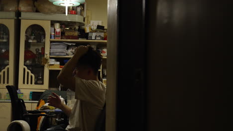 asian man straightens his hair while mirroring in his room, hongkong