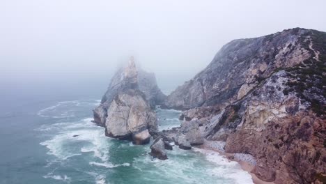 ascending shot of a moody, foggy beach at praia da ursa, portugal