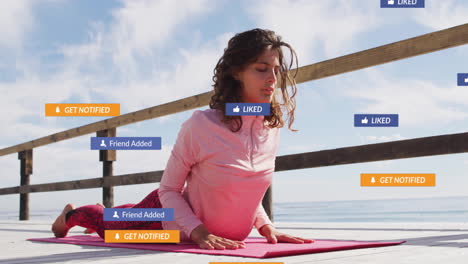 woman practicing yoga on seaside deck, showing pink mat and floating social media notifications