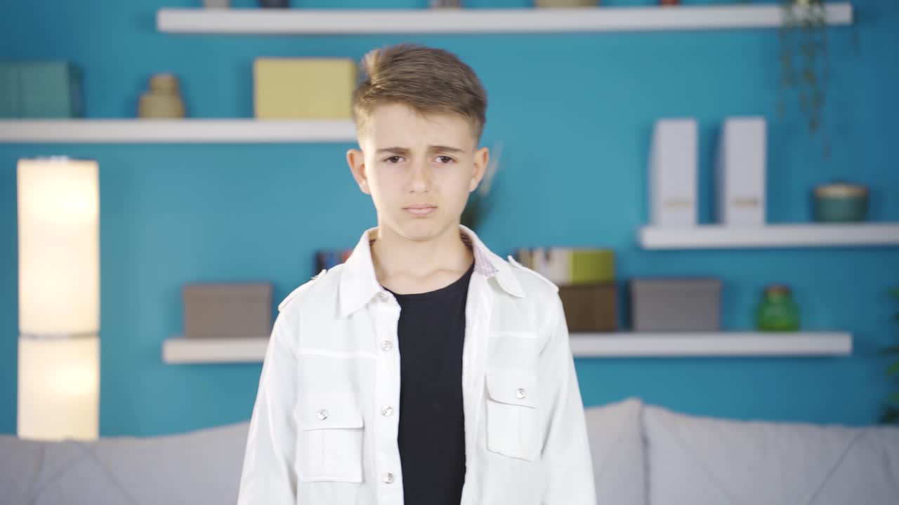 niño en casa mirando hacia atrás a la cámara con asco.