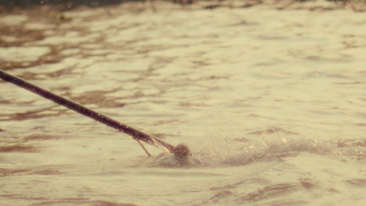 A fishing rod being cast in a river in Vietnam, with water splashing in focus