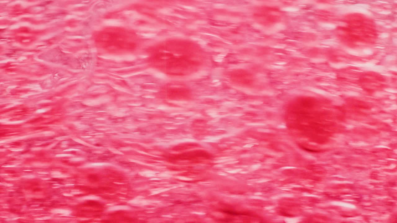 물 속에서 빠르게 움직이는 많은 붉은 거품의 매크로 샷