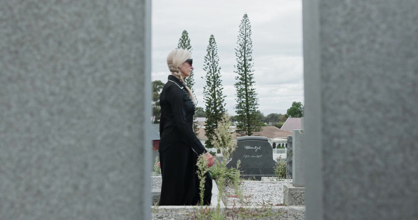 Persone in abiti scuri che camminano in un cimitero