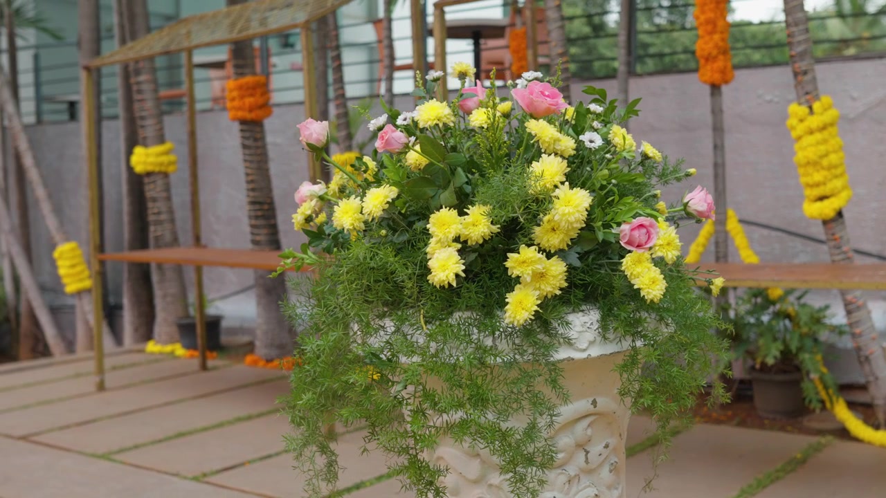 Large floral arrangement with yellow and pink flowers decorates outdoor wedding stage