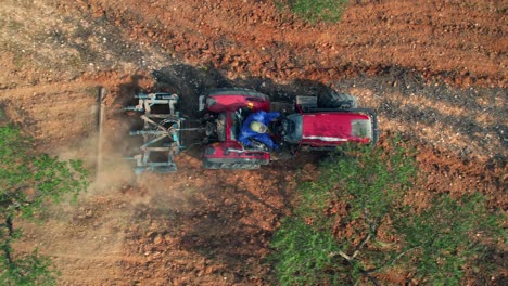 vista zenital aérea de un tractor que labra un campo de olivos