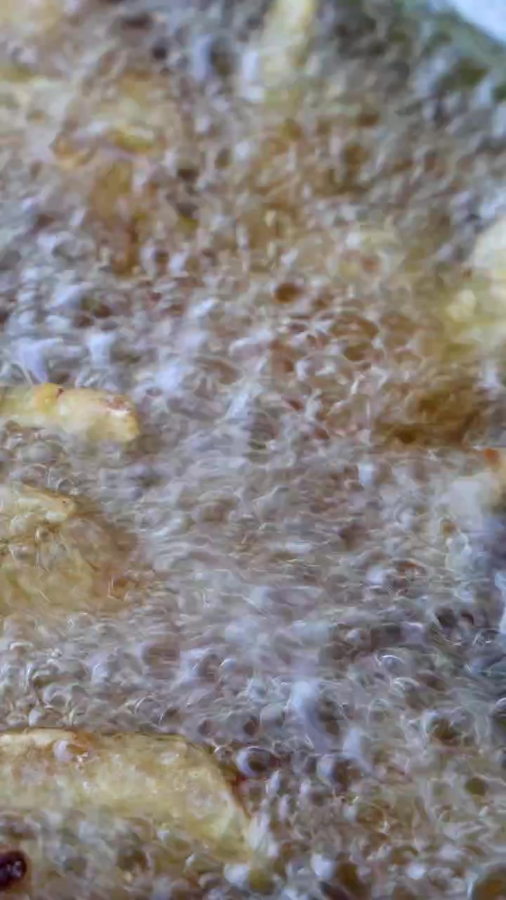 Potato fries rapidly frying in bubbling oil, close-up view, high heat, intense golden lighting