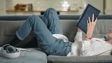 romantic woman lying on coach with photo album. smiling girl looking photobook