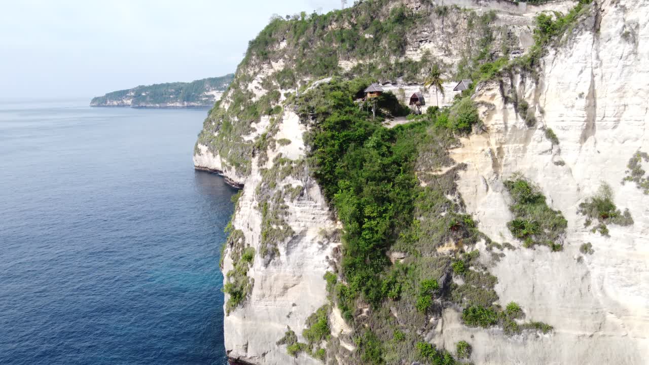 인도네시아 누사 페니다 섬 의 바위 가 많은 해안 에 있는 가파른 석회암 케이프 절벽 의 가장자리 에 있는 하마  ⁇  나무 집