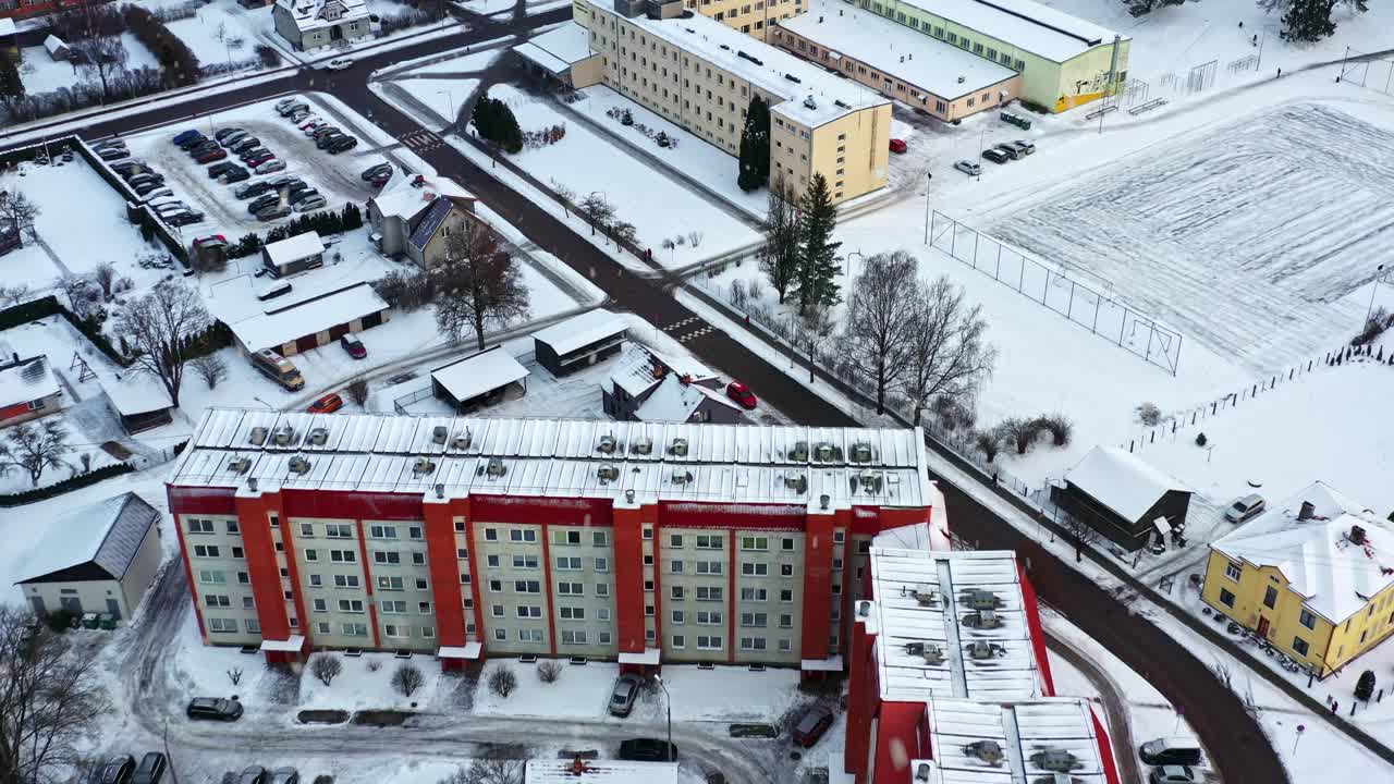 Boligkompleks dekket av snø i vintersesongen, sett fra luften med snøfall på en dyster dag.