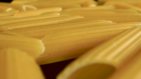 dolly hacia atrás macro shot de pasta italiana penne en mesa negra