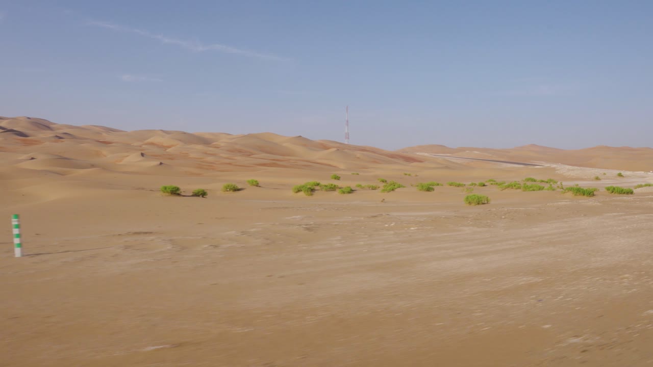 conduciendo a través de asombrosos caminos vacíos del desierto de abu dhabi con pequeños arbustos verdes en la base de las dunas de arena
