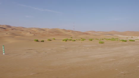 driving through amazing abu dhabi desert empty roads with small green shrubs at the base of sand dunes