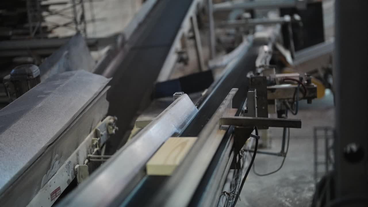Lumber conveyor system transporting cut wood through factory with mechanical precision, medium industrial backdrop