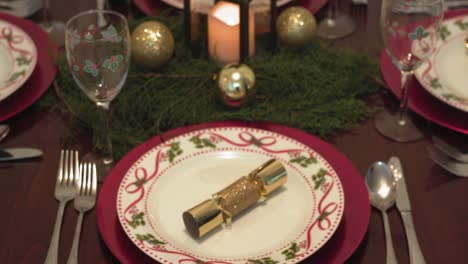 Pull-focus-on-Christmas-table-setting-and-gold-bonbon-on-wooden-table