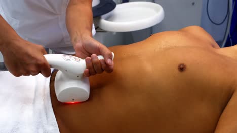 médico que realiza la depilación láser en un paciente masculino