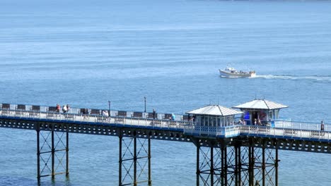 crucero turístico en barco pasando turistas cruzando el paseo marítimo del muelle de llandudno