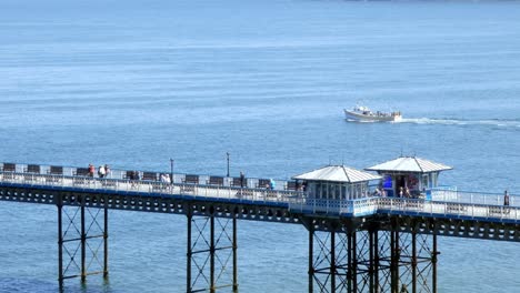 sightseeing boat cruise passing tourists crossing llandudno pier seafront promenade