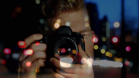 caucasian male photographer clicking pictures with digital camera against night city traffic