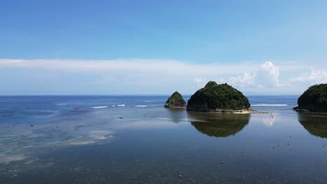 panoramic aerial view of shallow turquoise waters along a tropical lagoon with small islands and waves crashing