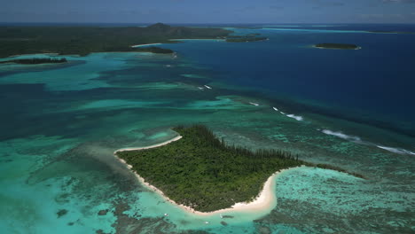 aerial pull back from ilot moro, revealing clear water of isle of pines in the background