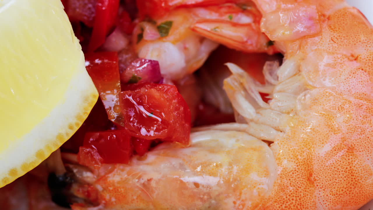 Close up of cooked shrimp with a slice of lemon and herbs on a white plate at a restaurant