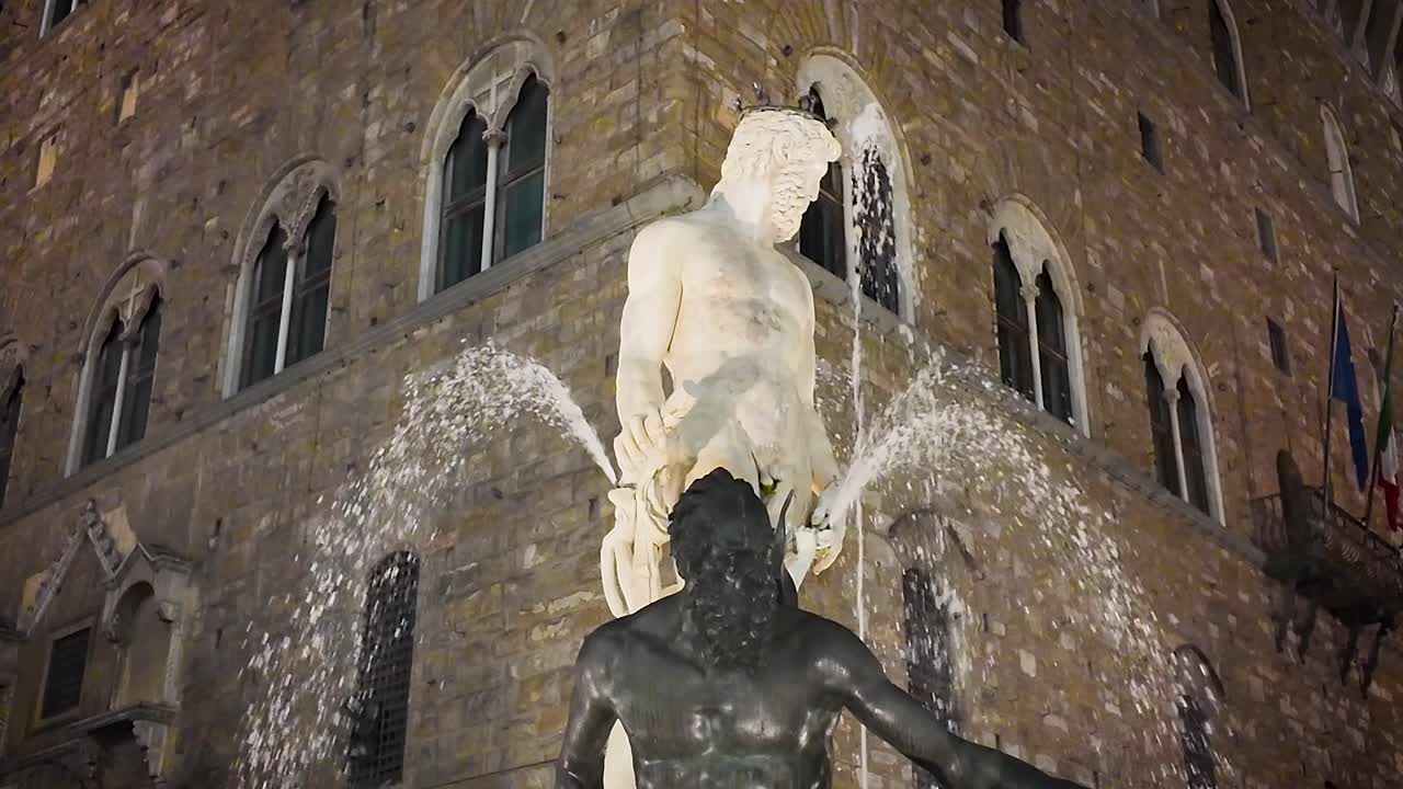 Static slow motion night view of the Neptune Fountain in Piazza della Signoria, capturing illuminated marble details and the timeless Renaissance atmosphere of central Florence