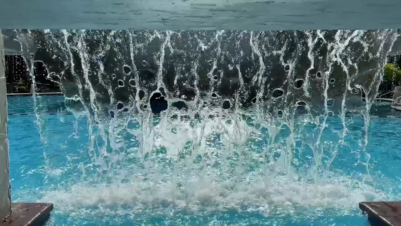 Slow Motion Underneath a Majestic Waterfall Cascading into a Pristine Swimming Pool