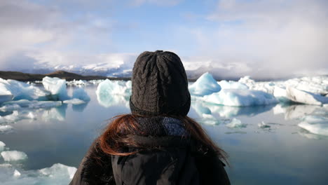 toma cinematográfica de una mujer disfrutando del paisaje y los pequeños icebergs que se encuentran en el parque nacional jökulsárlón en islandia