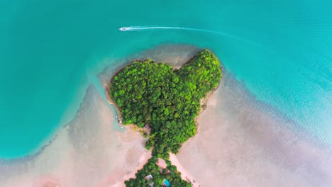 drone shot of heart shaped island in railay thailand with boats passing by