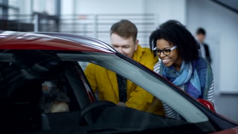 una pareja feliz con un niño probando un coche.