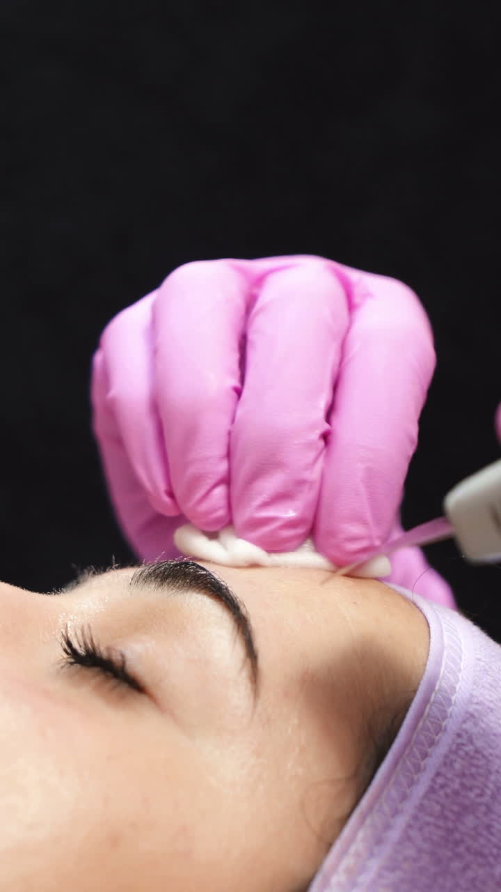 Beautiful woman in a beauty salon. Professional procedure of ultrasonic face cleansing. Cosmetologist job. Aesthetic cosmetology. Vertical video