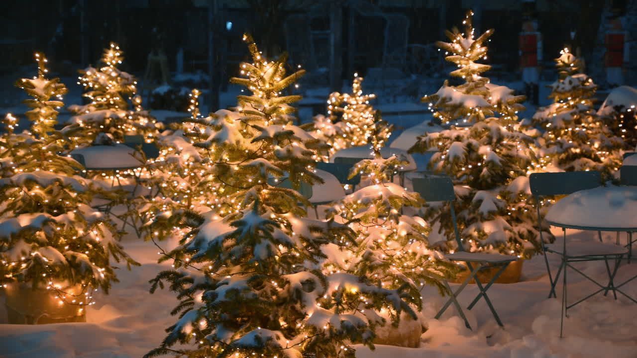 Seppelevalot joulukuusissa lumen peittämien sohvapöytien lähellä lumisateen aikana. Talvi-ilta Chișinăussa, Moldovassa