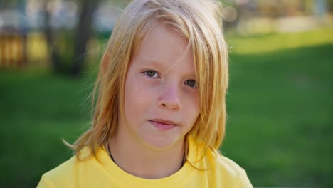 portrait of a boy in a yellow shirt in a park