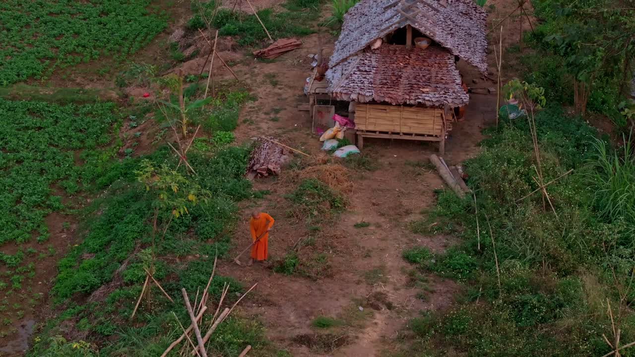 Lahan pertanian yang damai saat senja dengan para biksu yang bekerja di dekat gubuk sederhana, Thailand