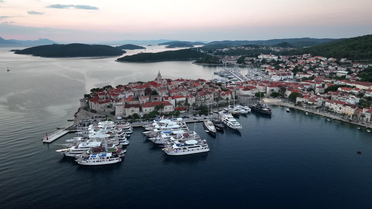 Aerial drone video flying to the left, panning around the old city of Korcula in Croatia at sunrise