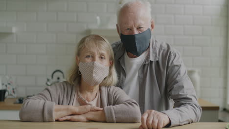 elderly couple wearing masks in kitchen