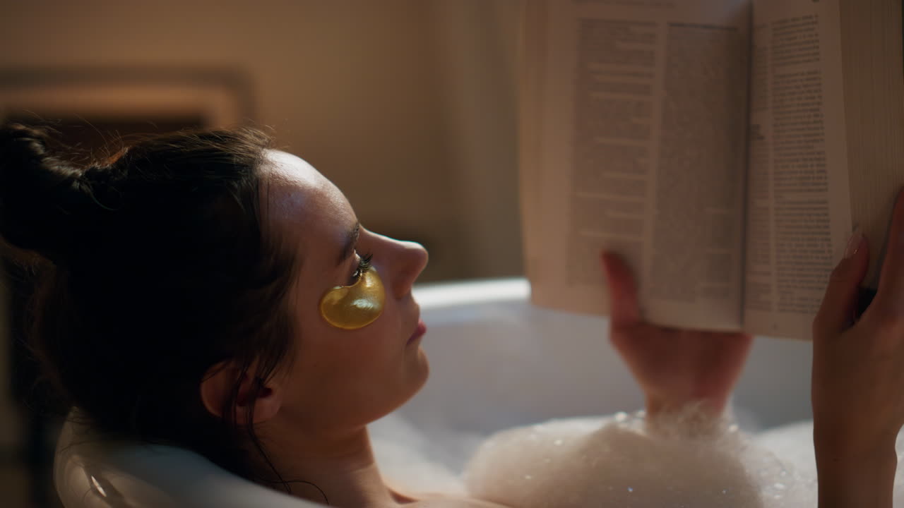 Spa model reading book chilling foam bath closeup. Woman enjoying hot bathtub