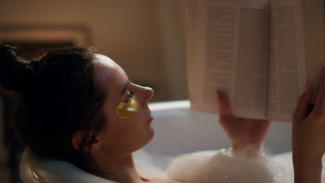 spa model reading book chilling foam bath closeup. woman enjoying hot bathtub