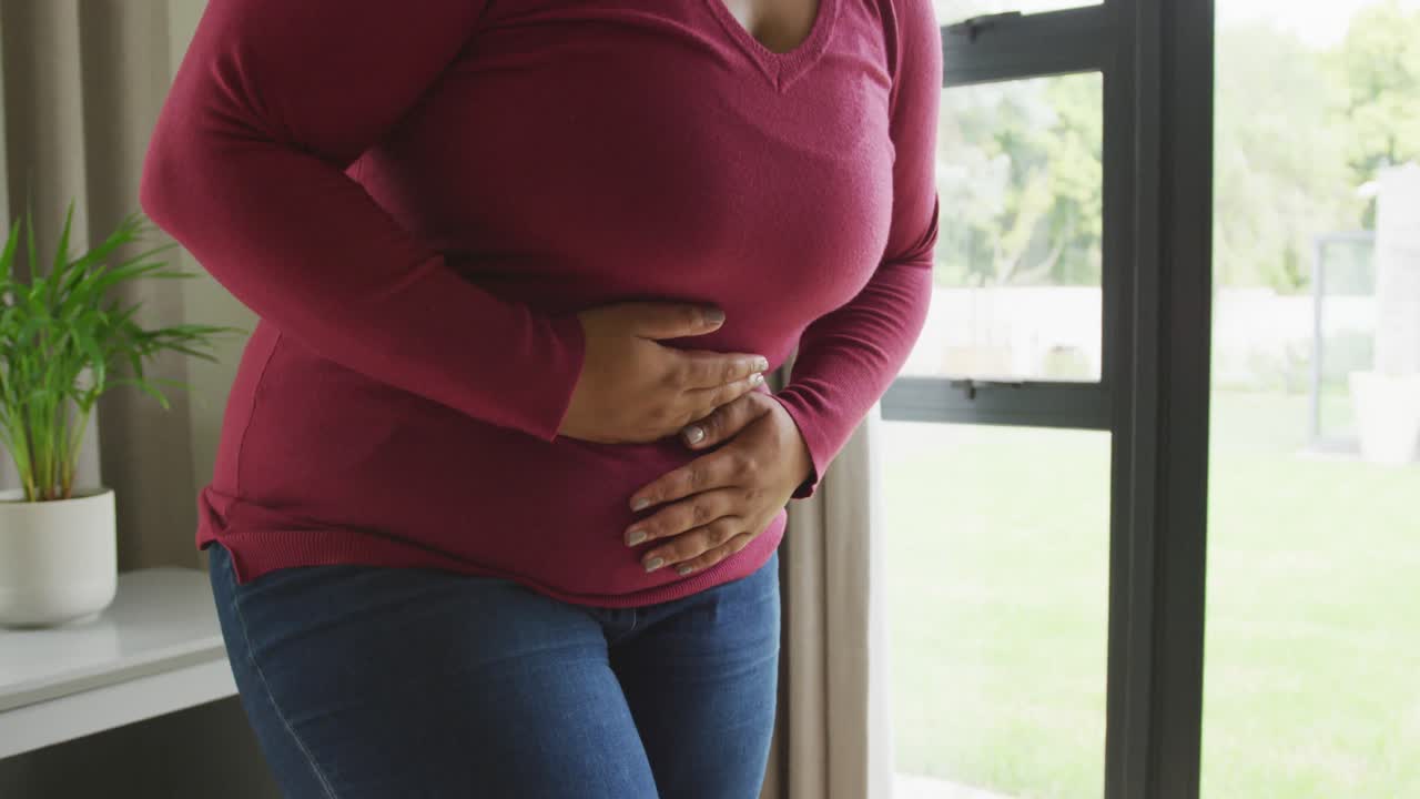 Video a mezzo busto di donna afroamericana formosa che ha mal di stomaco.