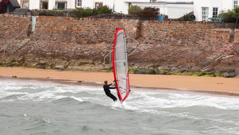 windsurfer navigating waves near a beach